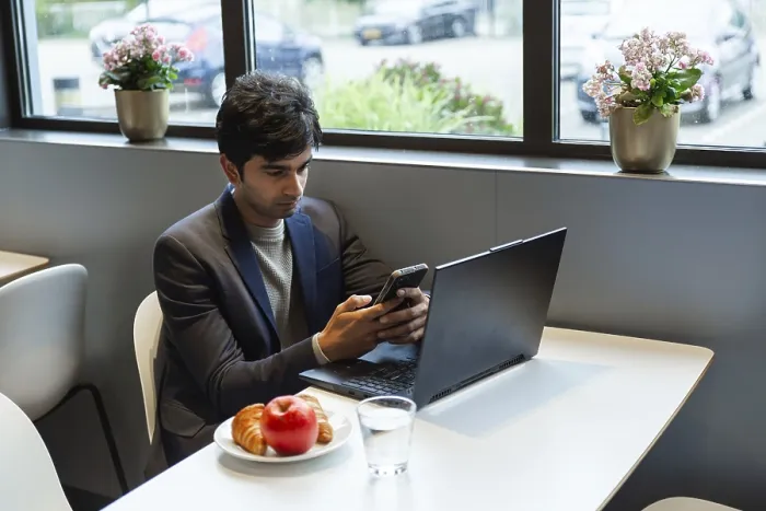 Gerahmter Druck : Ein indischer Mann multitaskt effizient mit einem Smartphone. Gerahmter Druck : Ein indischer Mann multitaskt effizient mit einem Smartphone.