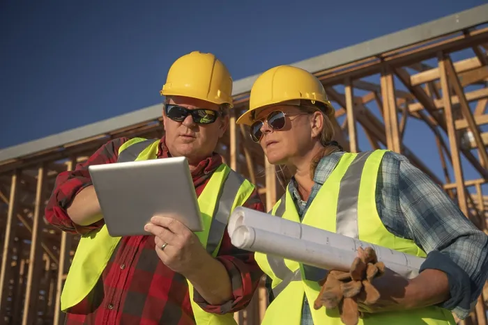 Gerahmter Druck : Männliche und weibliche Bauarbeiter, die an einem Computerpad auf der Baustelle arbeiten. Gerahmter Druck : Männliche und weibliche Bauarbeiter, die an einem Computerpad auf der Baustelle arbeiten.