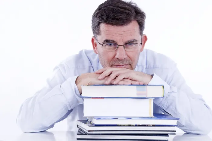 Gerahmter Druck : Ein Mann, 50+, lehnt sich an einen Stapel Bücher. Gerahmter Druck : Ein Mann, 50+, lehnt sich an einen Stapel Bücher.