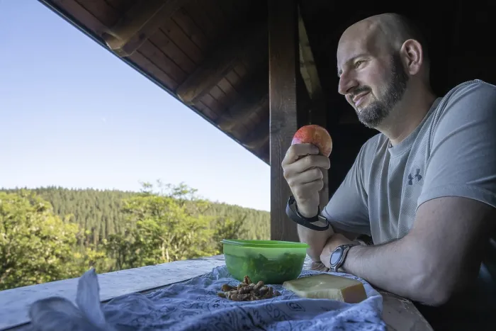 Gerahmter Druck : Ein Mann isst eine Apfel und schaut in den Wald. Gerahmter Druck : Ein Mann isst eine Apfel und schaut in den Wald.