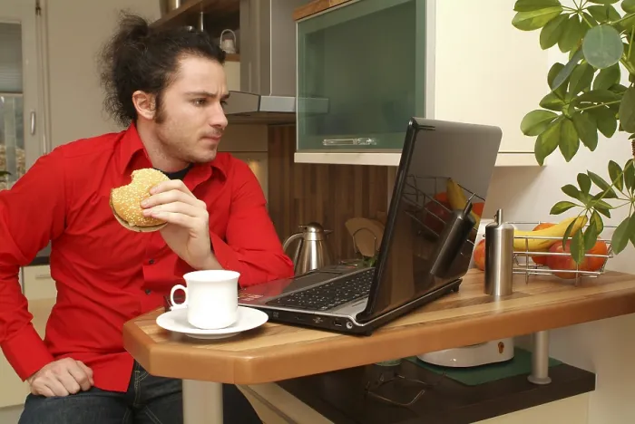 Gerahmter Druck : Mann isst Burger beim Laptop-gebrauch Gerahmter Druck : Mann isst Burger beim Laptop-gebrauch