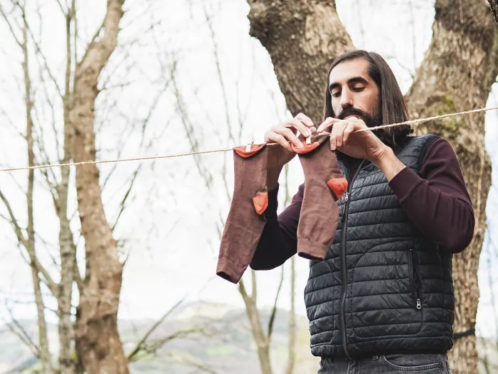 Gerahmter Druck : Ein Mann hängt Kleidung an einer Leine in einem Wald. Gerahmter Druck : Ein Mann hängt Kleidung an einer Leine in einem Wald.
