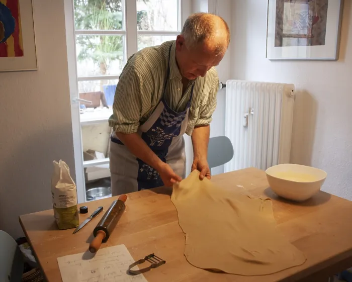 Gerahmter Druck : Ein Mann rollt Strudelteig an einem Tisch aus.
