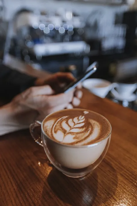 Gerahmter Druck : Ein Mann nutzt ein Smartphone in einem Café. Gerahmter Druck : Ein Mann nutzt ein Smartphone in einem Café.