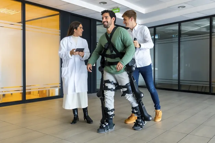 Gerahmter Druck : Mechanischer Exoskelett, weibliche Ärztin mit Gerät geht mit behindertem Menschen mit roboterischem Skelett in der Rehabilitation. Gerahmter Druck : Mechanischer Exoskelett, weibliche Ärztin mit Gerät geht mit behindertem Menschen mit roboterischem Skelett in der Rehabilitation.