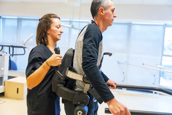 Gerahmter Druck : Mechanischer Exoskelett. Weibliche Physiotherapie-Helferin hilft behinderter Person mit roboterischem Skelett zu gehen. Gerahmter Druck : Mechanischer Exoskelett. Weibliche Physiotherapie-Helferin hilft behinderter Person mit roboterischem Skelett zu gehen.