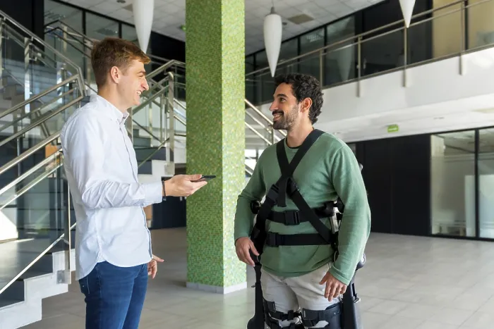 Gerahmter Druck : Mechanischer Exoskelett, Physiotherapeut schaut auf Beratung mit Tablet mit behindertem Menschen mit Roboter-Skelett. Gerahmter Druck : Mechanischer Exoskelett, Physiotherapeut schaut auf Beratung mit Tablet mit behindertem Menschen mit Roboter-Skelett.