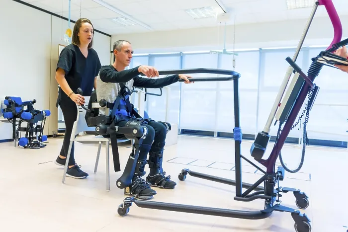 Gerahmter Druck : Mechanischer Exoskelett. Weibliche Physiotherapeutin-Assistentin hebt behindertes Menschen mit roboterischem Skelett, um aufzustehen. Gerahmter Druck : Mechanischer Exoskelett. Weibliche Physiotherapeutin-Assistentin hebt behindertes Menschen mit roboterischem Skelett, um aufzustehen.