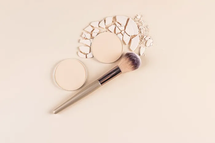 Gerahmter Druck : Obenansicht eines stilvollen Make-up-Angebots, das eine Kompakt-Puderform in ganzer und gebrochener Form zeigt. Gerahmter Druck : Obenansicht eines stilvollen Make-up-Angebots, das eine Kompakt-Puderform in ganzer und gebrochener Form zeigt.