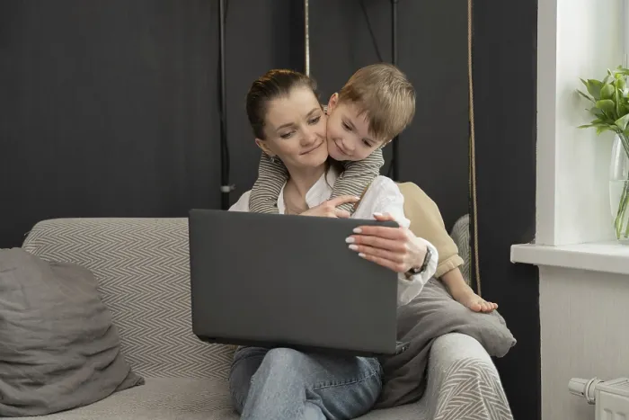 Gerahmter Druck : Eine Mutter sitzt auf einem Sofa und benutzt einen Laptop. Gerahmter Druck : Eine Mutter sitzt auf einem Sofa und benutzt einen Laptop.