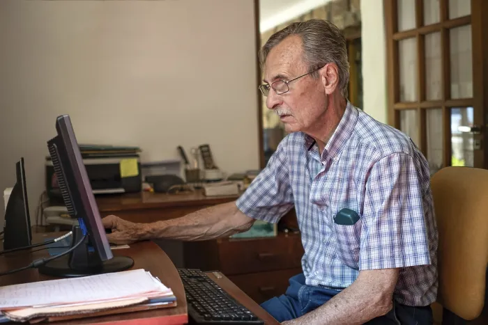Gerahmter Druck : Ein älterer Mann sitzt vor seinem Computer zu Hause.