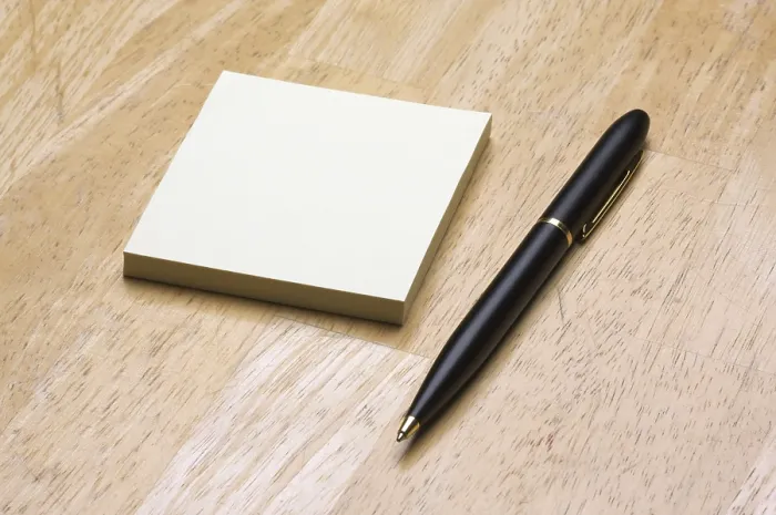 Gerahmter Druck : Feder und Post-it-Notizblock gegen einen Holz-Hintergrund. Gerahmter Druck : Feder und Post-it-Notizblock gegen einen Holz-Hintergrund.