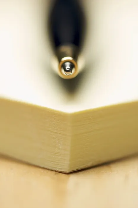 Gerahmter Druck : Feder und Post-it-Notizblock gegen einen Holzhintergrund. Gerahmter Druck : Feder und Post-it-Notizblock gegen einen Holzhintergrund.