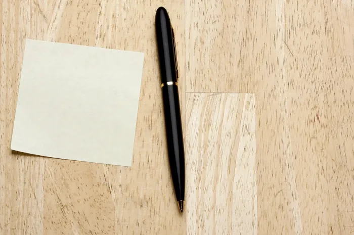 Gerahmter Druck : Feder und Post-it-Notizblock gegen einen Holz-Hintergrund. Gerahmter Druck : Feder und Post-it-Notizblock gegen einen Holz-Hintergrund.