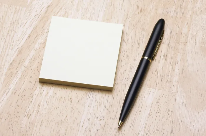 Gerahmter Druck : Feder und Post-it-Notizblock gegen einen Holzhintergrund. Gerahmter Druck : Feder und Post-it-Notizblock gegen einen Holzhintergrund.