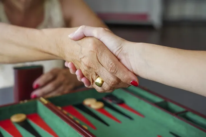 Gerahmter Druck : Zwei Menschen schütteln sich die Hand über einem Backgammon-Brett. Gerahmter Druck : Zwei Menschen schütteln sich die Hand über einem Backgammon-Brett.