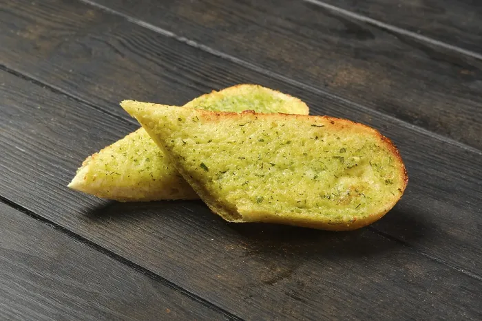 Gerahmter Druck : Zwei Stücke Knoblauchbrot auf einem Tisch. Gerahmter Druck : Zwei Stücke Knoblauchbrot auf einem Tisch.
