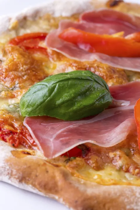 Gerahmter Druck : Ein Detail einer Pizza mit Schinken und Basilikum. Gerahmter Druck : Ein Detail einer Pizza mit Schinken und Basilikum.