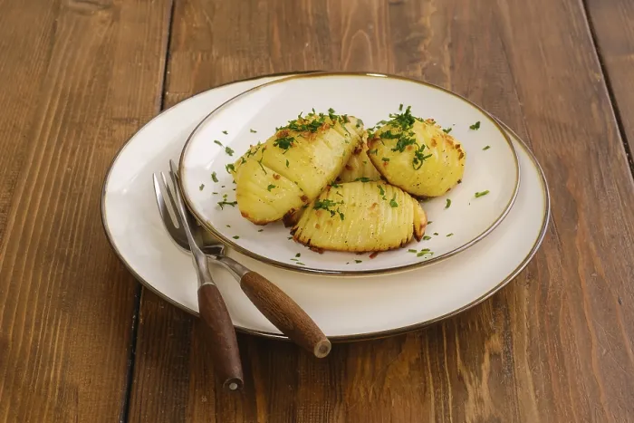 Gerahmter Druck : Eine Portion knuspriger Hasselback-Kartoffel auf einem Teller. Gerahmter Druck : Eine Portion knuspriger Hasselback-Kartoffel auf einem Teller.