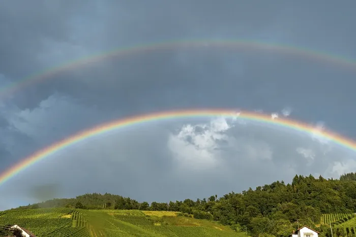 Gerahmter Druck : Ein Regenbogen wird im Himmel über einem Hügelgipfel gesehen. Gerahmter Druck : Ein Regenbogen wird im Himmel über einem Hügelgipfel gesehen.