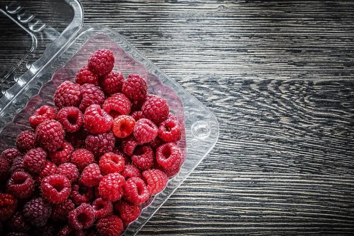 Gerahmter Druck : Raspberry in Behälter auf Holzteller.