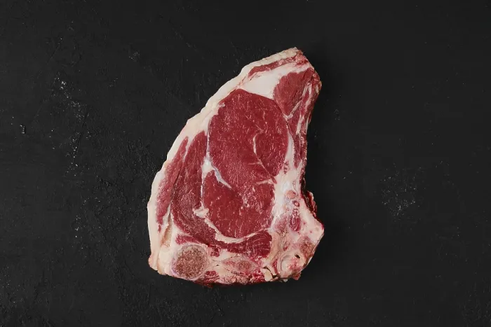 Gerahmter Druck : Rohes Lendensteak mit Knochen auf dunklem Hintergrund Gerahmter Druck : Rohes Lendensteak mit Knochen auf dunklem Hintergrund