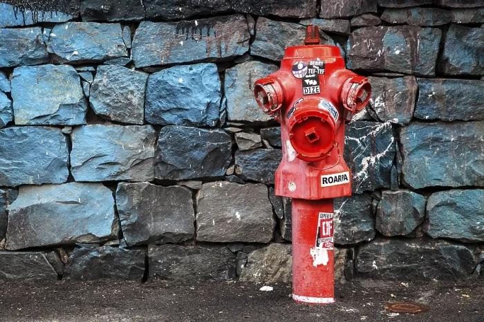 Gerahmter Druck : Roter Feuerwehrhahn vor einem Steinmauer. Gerahmter Druck : Roter Feuerwehrhahn vor einem Steinmauer.