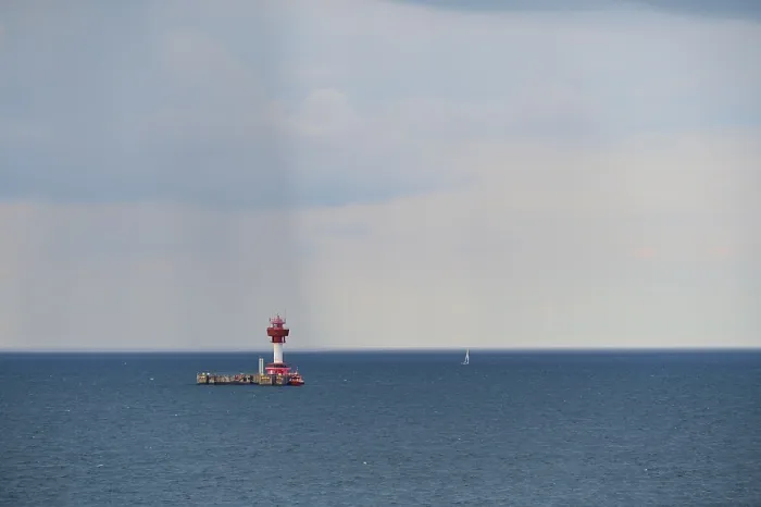 Gerahmter Druck : Ein roter Leuchtturm steht auf einem ruhigen.