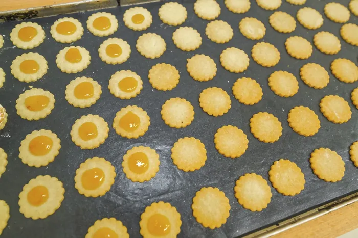 Gerahmter Druck : Reihen von Biskuits mit Orangengefüll auf einem Backblech. Gerahmter Druck : Reihen von Biskuits mit Orangengefüll auf einem Backblech.