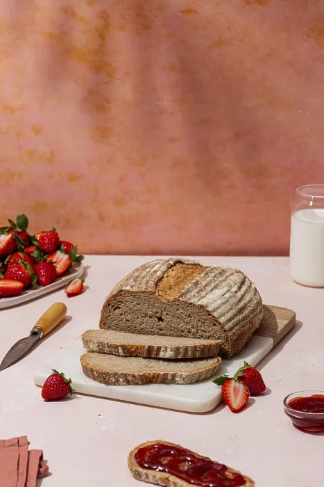 Gerahmter Druck : Ein rustikaler Laib Brot wird auf einem Schneidebrett geschnitten. Gerahmter Druck : Ein rustikaler Laib Brot wird auf einem Schneidebrett geschnitten.