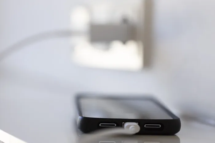 Gerahmter Druck : Ein Smartphone wird über eine Steckdose aufgeladen. Gerahmter Druck : Ein Smartphone wird über eine Steckdose aufgeladen.