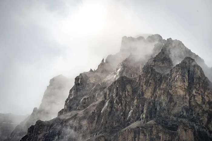Gerahmter Druck : Schneebedeckter Gipfel eines Berges, der von Wolken bedeckt ist.