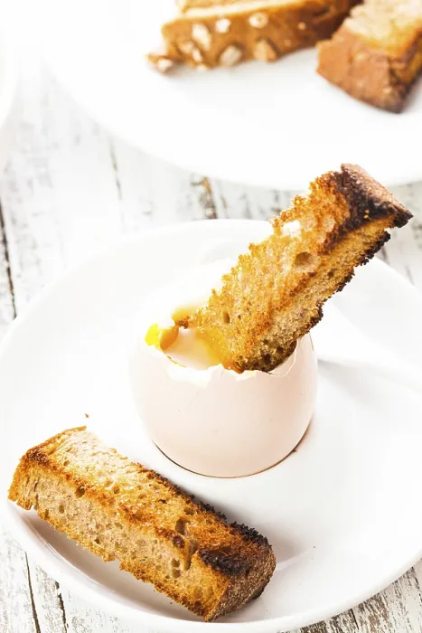 Gerahmter Druck : Ein weichgekochtes Ei in einem Eierbecher mit Toastbrot.