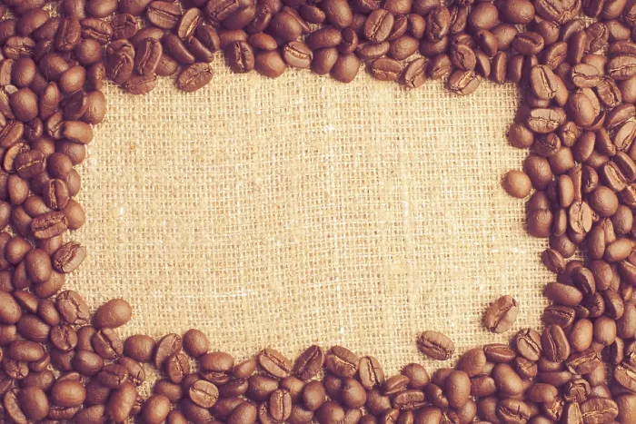 Gerahmter Druck : Kaffebohnen fallen über ein Jutesacktuch.