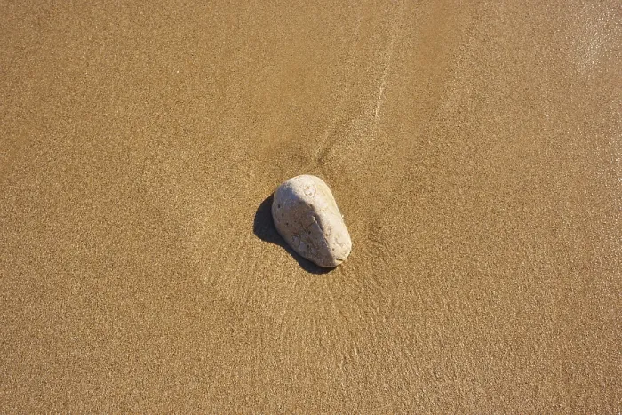 Gerahmter Druck : Ein Stein liegt im Sand auf einer Strand. Gerahmter Druck : Ein Stein liegt im Sand auf einer Strand.
