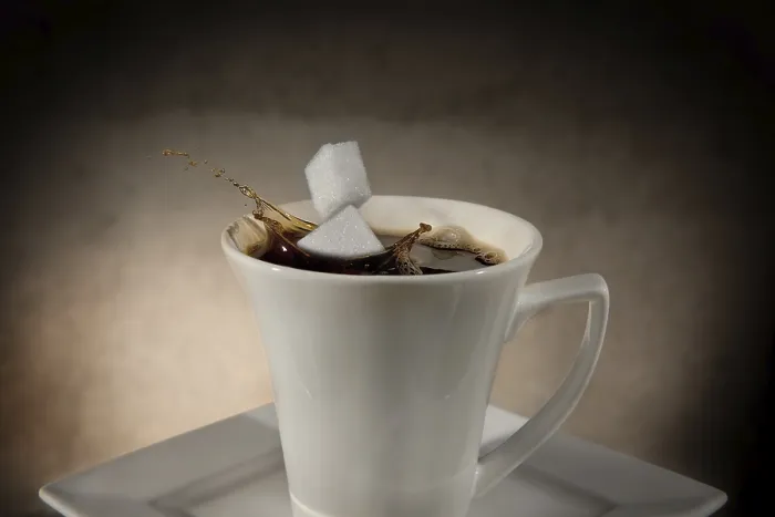Gerahmter Druck : Zwei Zuckerwürfel fallen in einen Kaffeebecher. Gerahmter Druck : Zwei Zuckerwürfel fallen in einen Kaffeebecher.