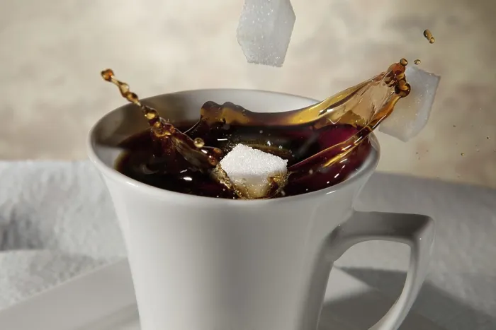 Gerahmter Druck : Zuckerwürfel fallen in ein Tassen Kaffee.