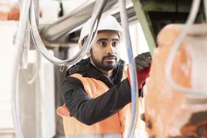 Gerahmter Druck : Techniker mit Bart und Helm arbeitet in einer Werkstatt. Gerahmter Druck : Techniker mit Bart und Helm arbeitet in einer Werkstatt.