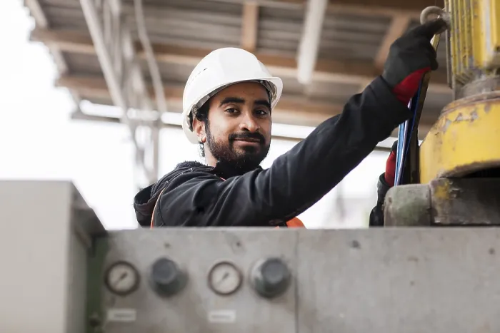 Gerahmter Druck : Techniker mit Bart und Helm arbeitet in einer Werkstatt. Gerahmter Druck : Techniker mit Bart und Helm arbeitet in einer Werkstatt.