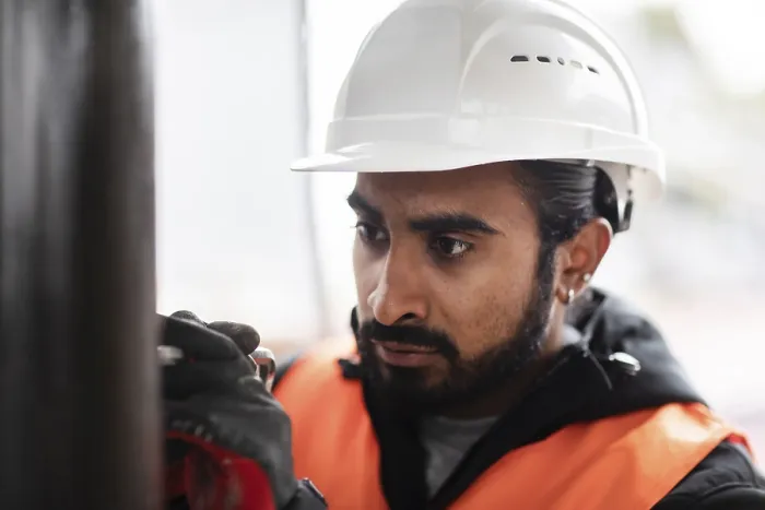 Gerahmter Druck : Techniker mit Bart und Helm arbeitet in einer Werkstatt. Gerahmter Druck : Techniker mit Bart und Helm arbeitet in einer Werkstatt.