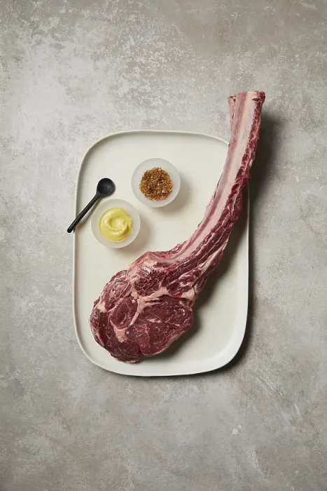Gerahmter Druck : Blick von oben auf eine rohe Tomahawk-Steak, die auf einem Keramiktablett präsentiert wird. Gerahmter Druck : Blick von oben auf eine rohe Tomahawk-Steak, die auf einem Keramiktablett präsentiert wird.