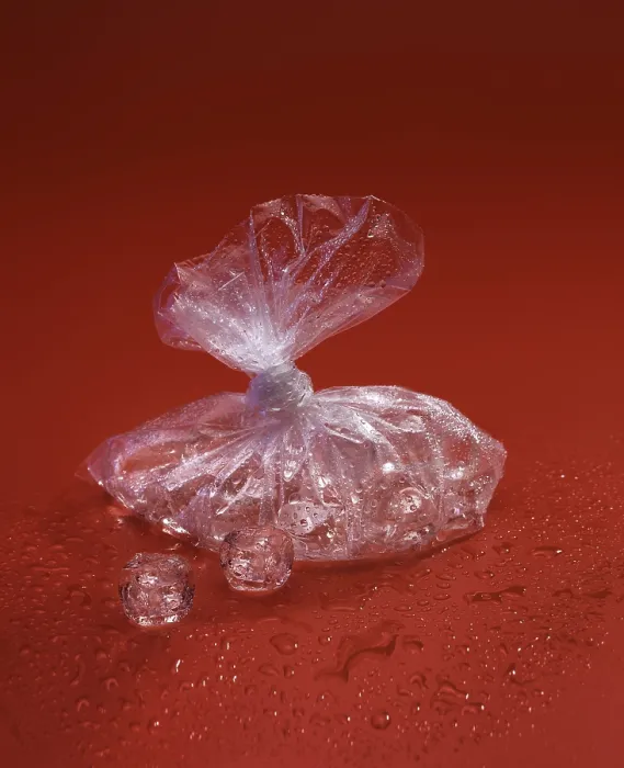 Gerahmter Druck : Transluzenter Plastikbeutel mit Eiskuben auf einer roten Oberfläche. Gerahmter Druck : Transluzenter Plastikbeutel mit Eiskuben auf einer roten Oberfläche.