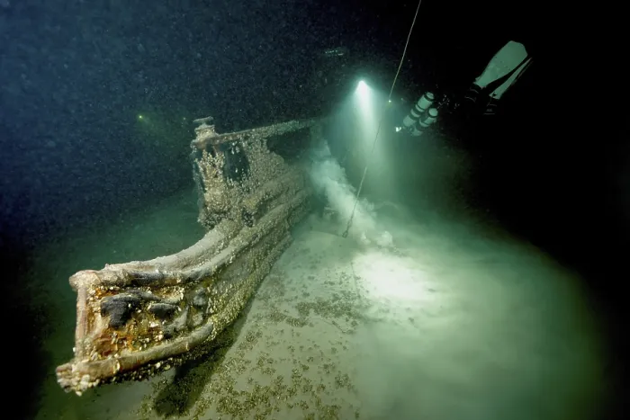 Gerahmter Druck : Unterwasserbild eines Tauchers, der sich einem Schiffswrack mit einer Lichtquelle nähert. Gerahmter Druck : Unterwasserbild eines Tauchers, der sich einem Schiffswrack mit einer Lichtquelle nähert.