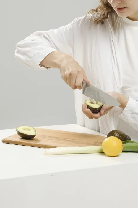 Gerahmter Druck : Eine unkenntliche Frau entfernt eine Stein aus einer Avocado mit einem Messer. Gerahmter Druck : Eine unkenntliche Frau entfernt eine Stein aus einer Avocado mit einem Messer.