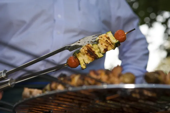 Gerahmter Druck : Ein Gemüse wird auf einem Grill mit Speichel bestrichen, während der Koch es umdreht.