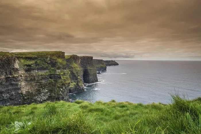 Gerahmter Druck : Blick über die Kliffs of Moher bei einem bewölkten Himmel.