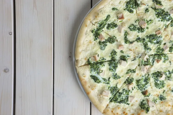 Gerahmter Druck : Obenansicht der Hälfte einer Pizza mit Spinat und Huhn. Gerahmter Druck : Obenansicht der Hälfte einer Pizza mit Spinat und Huhn.