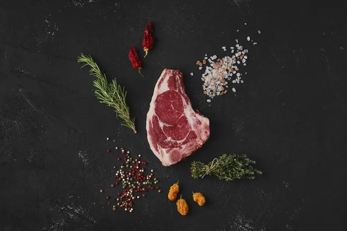 Gerahmter Druck : Rindersteak mit Knochen, Topansicht auf dunklem Hintergrund Gerahmter Druck : Rindersteak mit Knochen, Topansicht auf dunklem Hintergrund