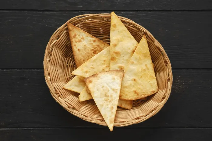 Gerahmter Druck : Obenansicht von einer Tortilla, die auf dreieckige Scheiben geschnitten wurde, in einem Weidenkorb auf einem Tisch. Gerahmter Druck : Obenansicht von einer Tortilla, die auf dreieckige Scheiben geschnitten wurde, in einem Weidenkorb auf einem Tisch.