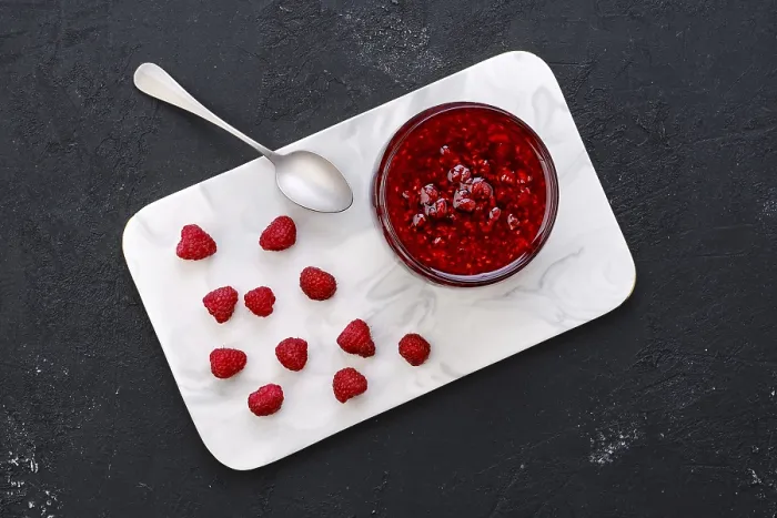 Gerahmter Druck : Obenansicht eines durchsichtigen Topfes mit Himbeermarmelade. Gerahmter Druck : Obenansicht eines durchsichtigen Topfes mit Himbeermarmelade.